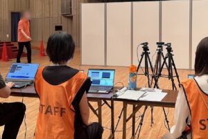 Product is demonstrated at a health festival. Staff observe a man walking in front of cameras.
