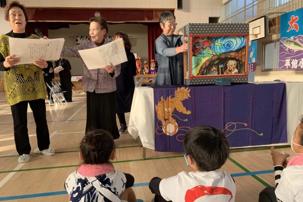 Older women share the local myths through a paper theater program from children